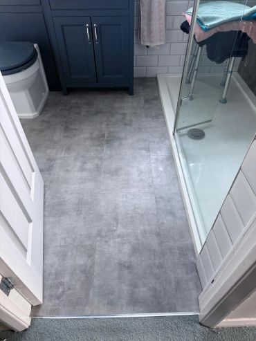 Clean bathroom with grey flooring and glass shower.