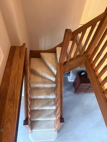 Wooden staircase with beige carpet steps.