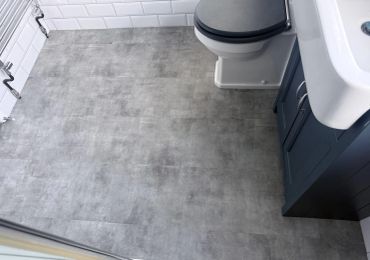 Modern bathroom with gray tile flooring and dark vanity.