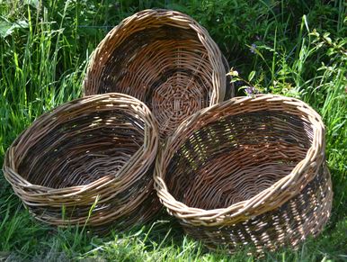 Three round willow baskets set against natural green grass