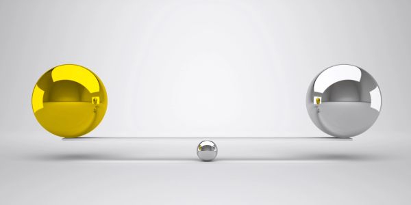 Two large reflective spheres balancing with a small one between.