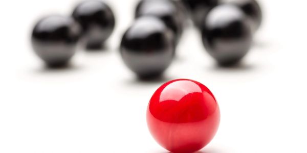 A single red ball in front of multiple black balls.