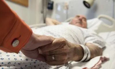Hospital patient in hospital bed holding family's hand