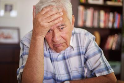 Elderly man with forehead in hand