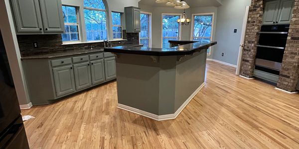Spacious kitchen with wooden floors, gray cabinets, and a central island.