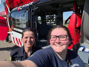 Two women smiling in front of a UW medical helicopter.