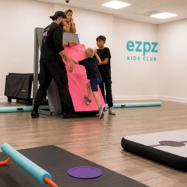 Instructor helps kids with climbing activity at ezpz Kids Club.