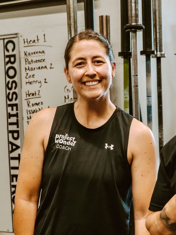 Smiling coach in a gym with CrossFit and workout equipment.