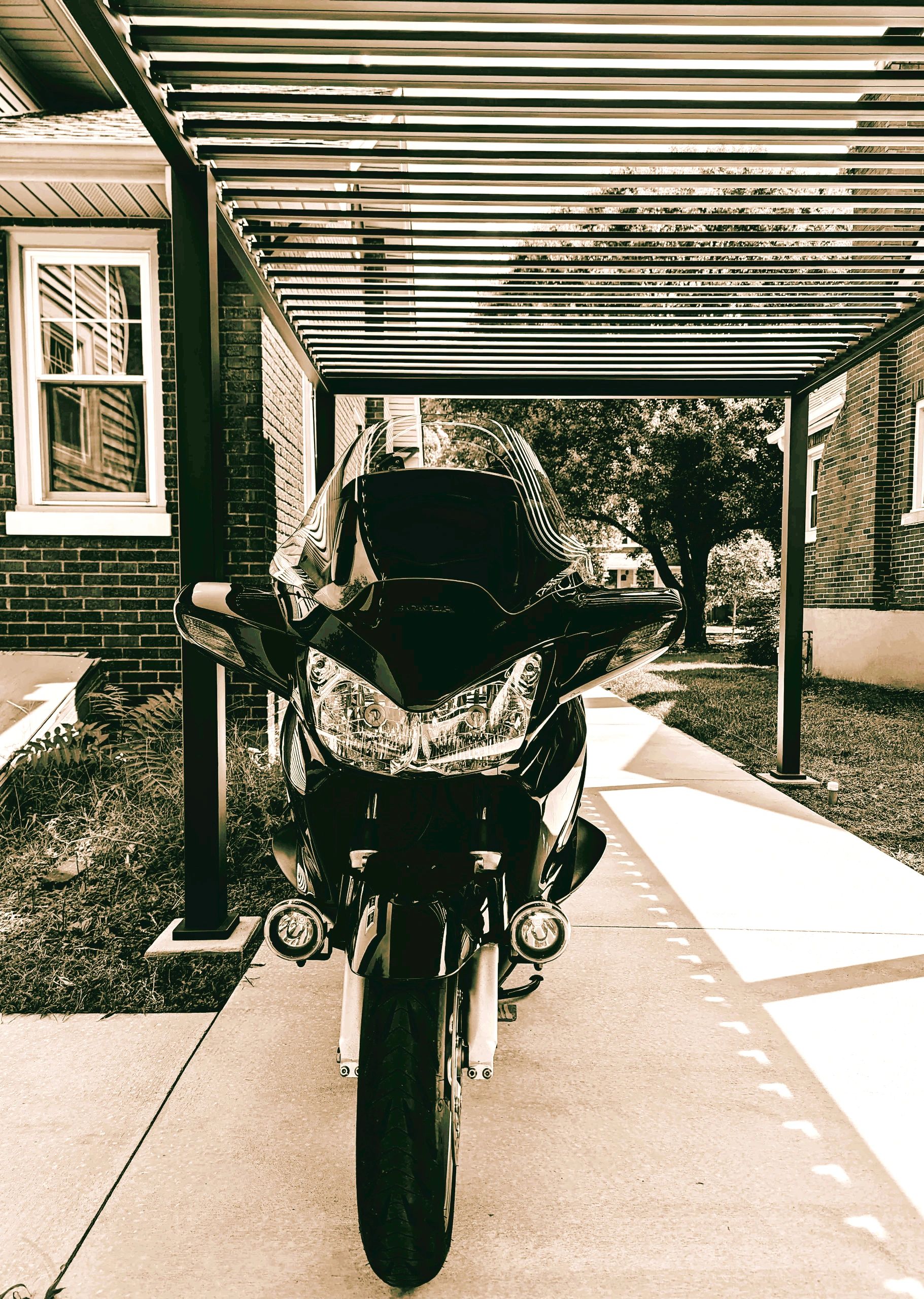 Black motorcycle parked under a pergola.