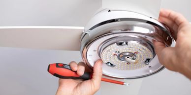 Person installing or repairing a ceiling light fixture with a screwdriver.