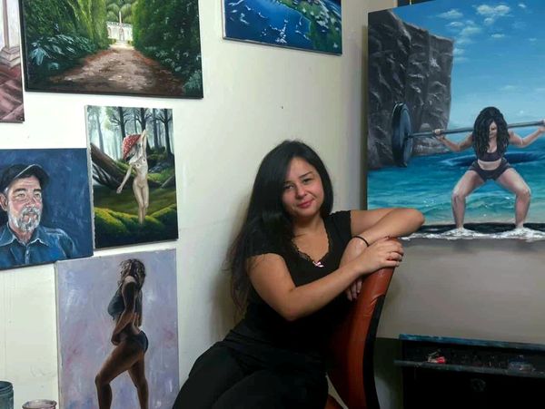 Woman sitting in an art studio surrounded by paintings.