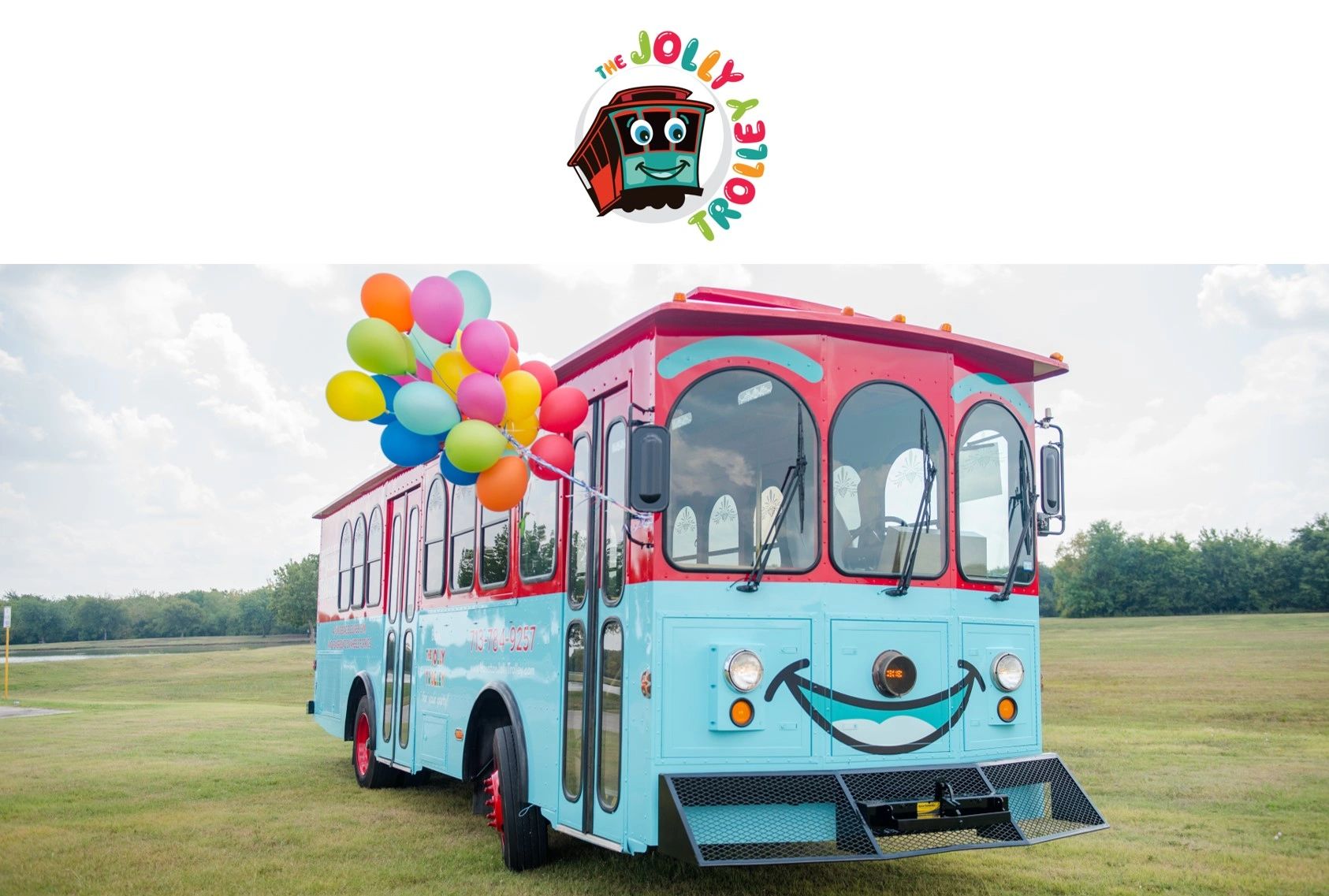 A colorful trolley adorned with balloons in a grassy field under a cloudy sky.