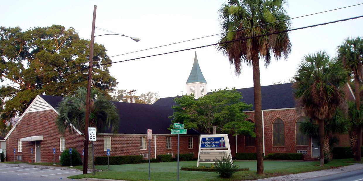 Brick Butler Presbyterian Church with palm trees and a speed limit sign.