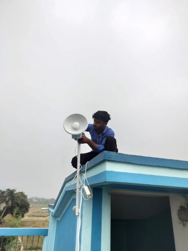 Man fixing a lamp on a rooftop.