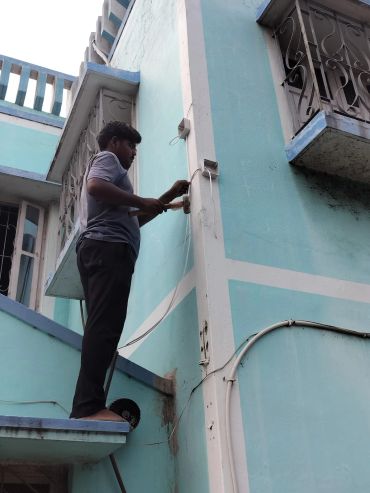Man painting wall while standing outside.