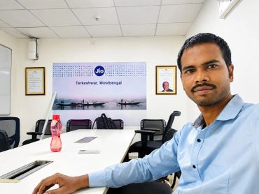 Man in blue shirt takes selfie in office meeting room.