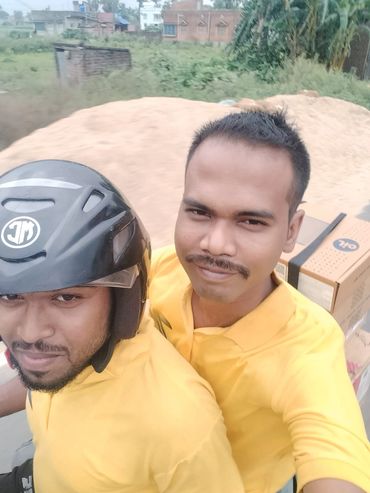 Two men in yellow shirts on a bike, one wearing a helmet.