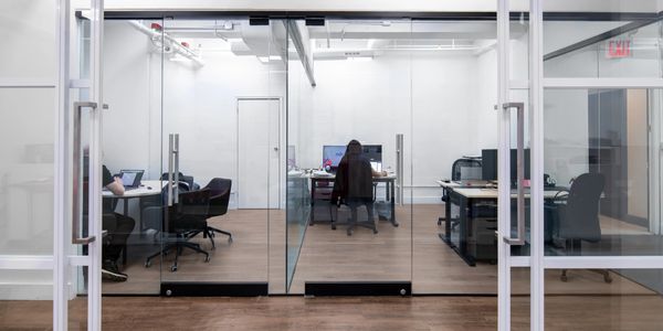 Modern office space with glass walls and people working at desks.