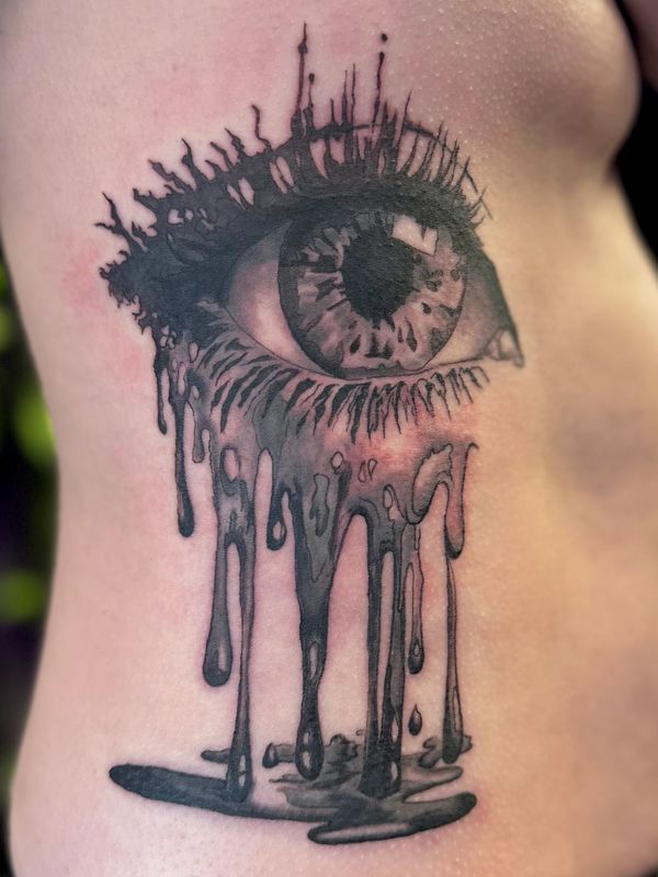 Tattoo of a melting eye with dripping effects.