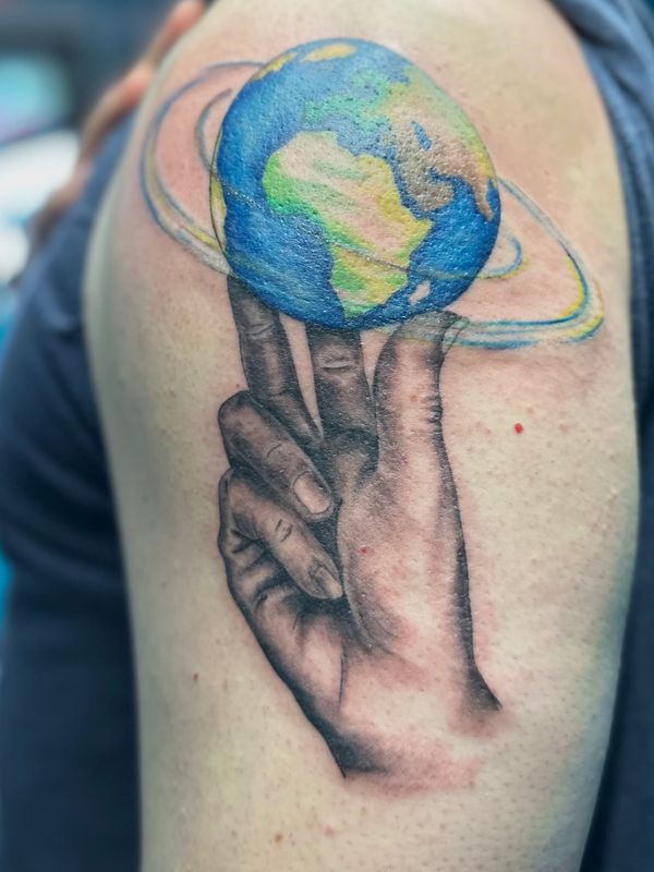 Illustrative tattoo of the Earth balanced on fingertips with blue and green color details.