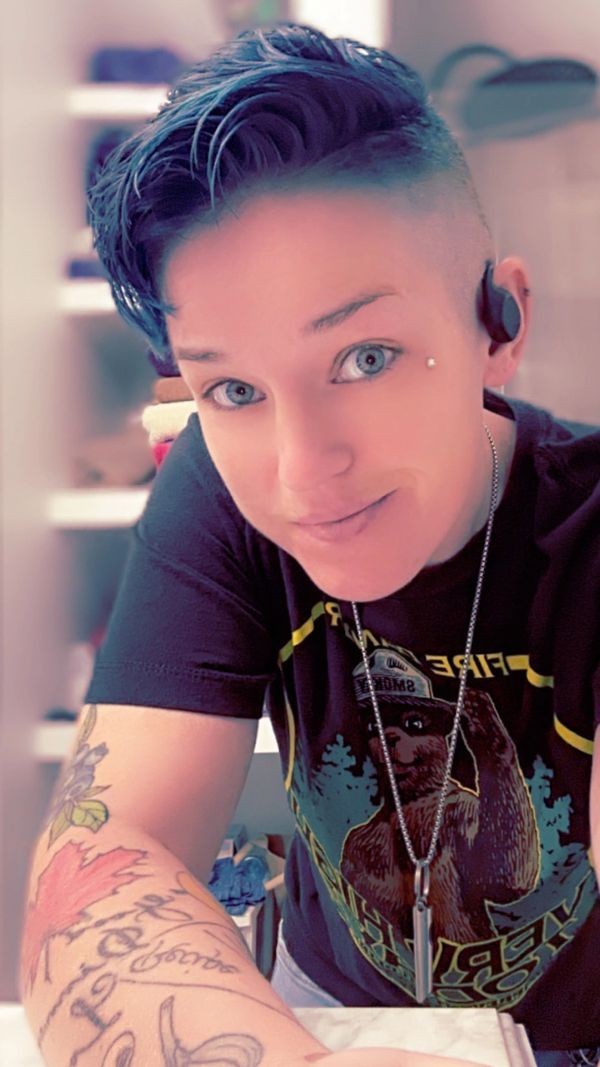 Person smiling with tattoos and blue eyes.