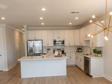 Modern white kitchen with island and stainless steel appliances.