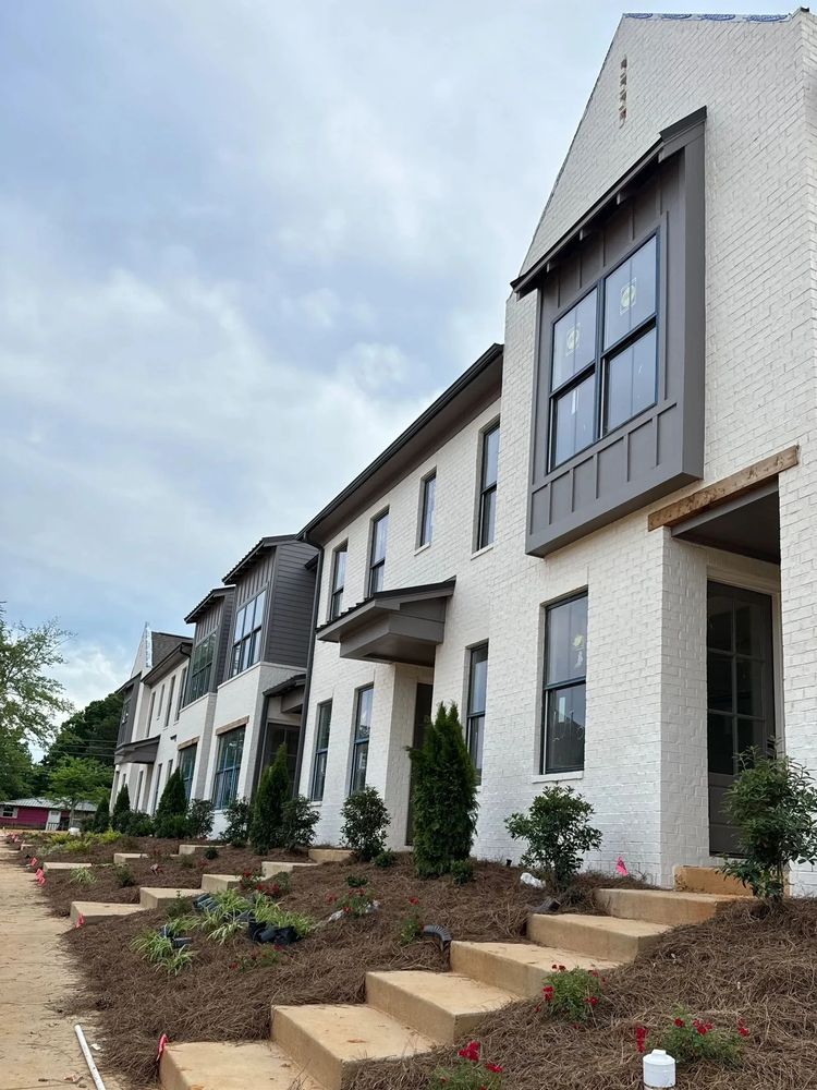 Newly built white brick townhouses with landscaping.