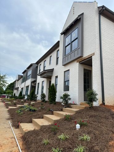 Row of modern townhouses with landscaped front yards and stone steps.