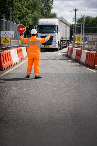 Construction worker directing truck traffic with a stop sign.