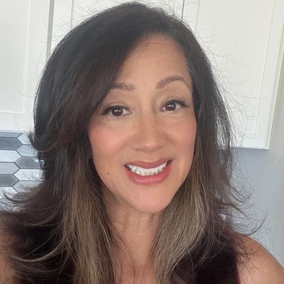A smiling woman with long dark hair and subtle makeup.