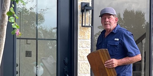 Man holding wood plank near a front door.