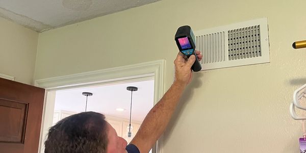 Person using thermal camera near a vent.