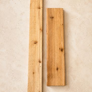 Two wooden planks with natural knots on a light surface.