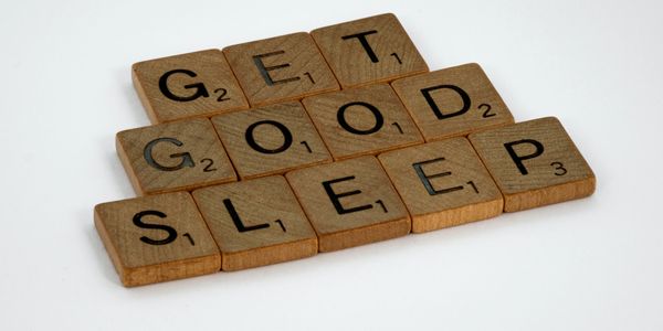 A white surface with brown Scrabble tiles spelling "Get Good Sleep"