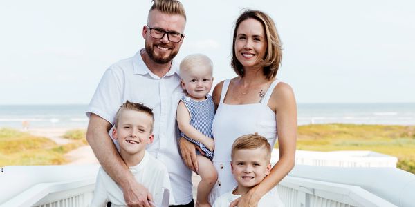 Happy family of five posing outdoors near the beach.