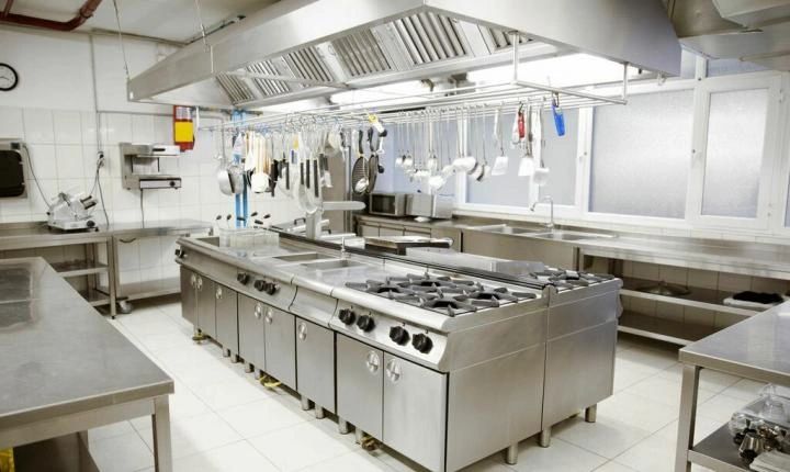 room of kitchen in a restaurant with stoves and stainless steel tables and white floors