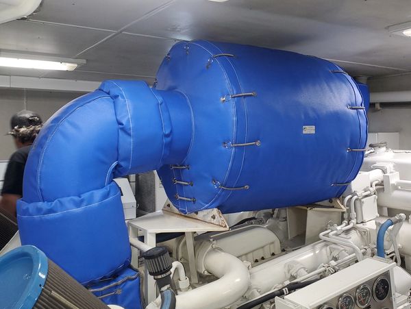 Large blue insulated cover over a piece of machinery, possibly an engine component, in an industrial