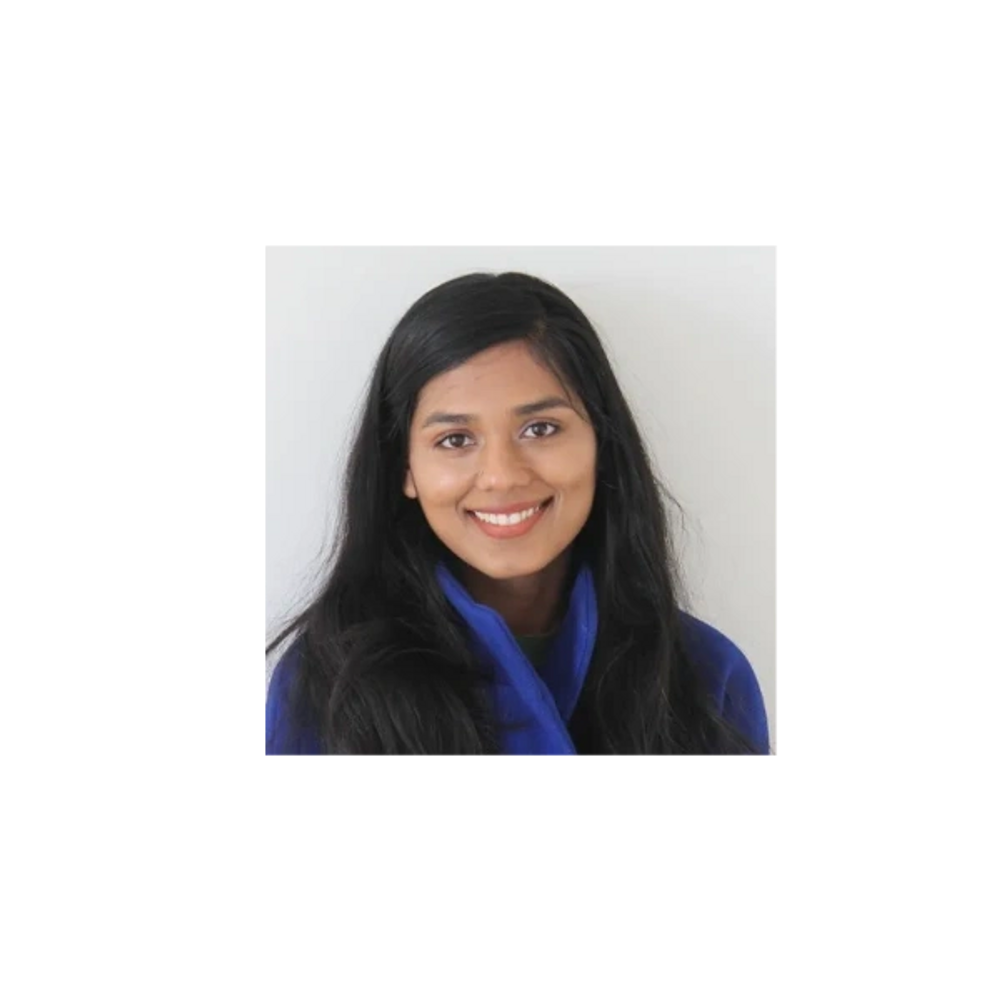 A young woman with long black hair and a friendly smile wearing a blue jacket.