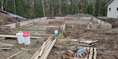 Foundation work at a construction site in a wooded area.