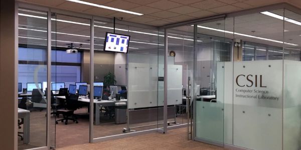 Modern office space with glass walls and computer workstations.