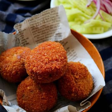 Golden-brown crispy fried snacks served on newspaper-lined plate.