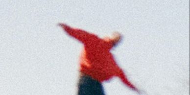 Blurred image of a person with arms outstretched.