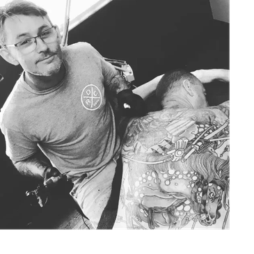 Tattoo artist working on a detailed back tattoo.