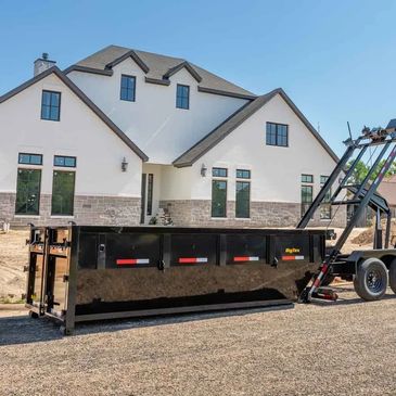 Large dumpster in front of a modern house.