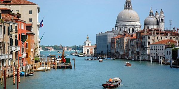 Venetian canal with boats and historic buildings under a clear sky.