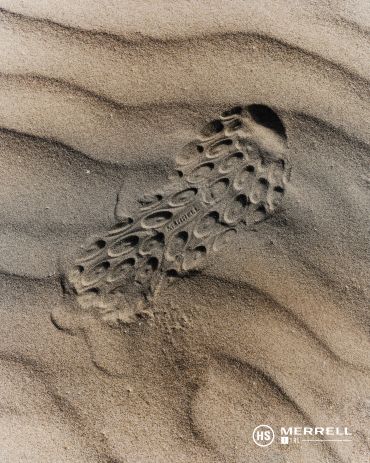 Shoe print on wavy sand surface at the beach.