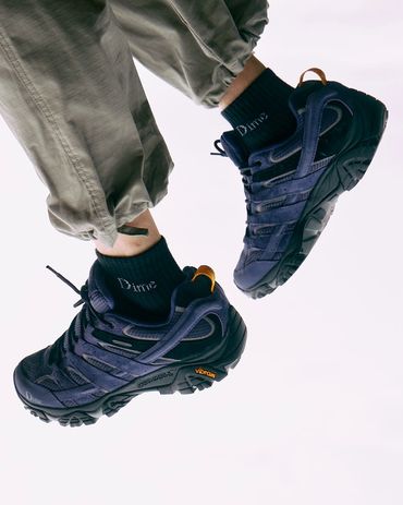 Close-up of black sneakers with Vibram soles and black socks.
