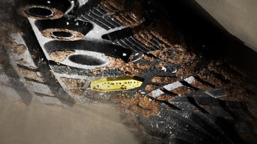 Close-up of a dirty, mud-covered shoe sole with intricate tread patterns.