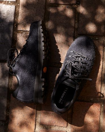 Black Merrell shoes placed on a brick surface with shadow play.