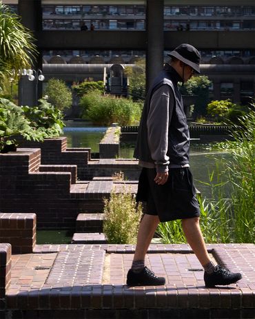 Man in casual wear walks by a modern water feature in an urban park.